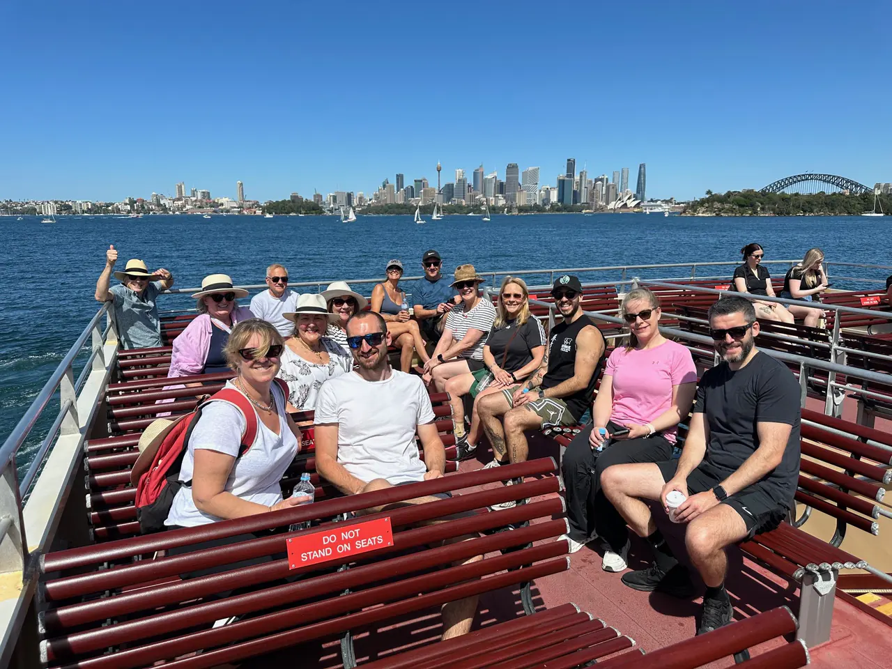 Studio 84 members on a ferry with the Harbour Bridge and city behind them, celebrating the studio’s 9th birthday